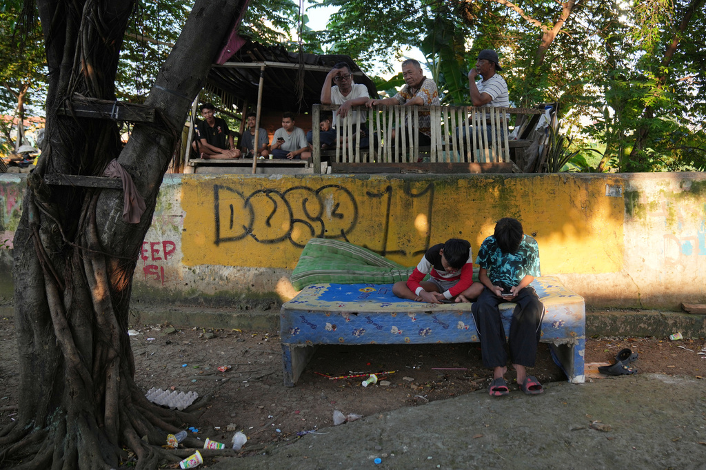 Teenage boys use their mobile phone in Jakarta, Indonesia, March 16, 2026. (AP Photo/Dita Alangkara)