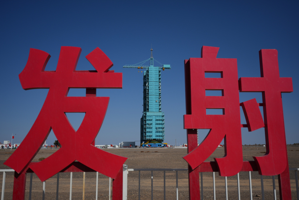 The Shenzhou-21 spacecraft sitting atop a Long March rocket covered on a launch pad is seen near the Chinese characters for launch, at the Jiuquan Satellite Launch Center in northwest China, Thursday, Oct. 30, 2025. (AP Photo/Andy Wong)