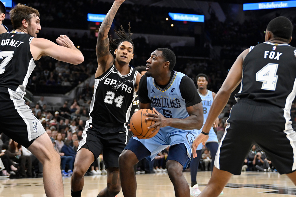 Memphis Grizzlies guard Vince Williams Jr. (5) drives against San Antonio Spurs guard Devin Vassell (24) and Spurs center Luke Kornet (7) during the first half of an NBA basketball game, Tuesday, Nov. 18, 2025, in San Antonio. (AP Photo/Darren Abate)