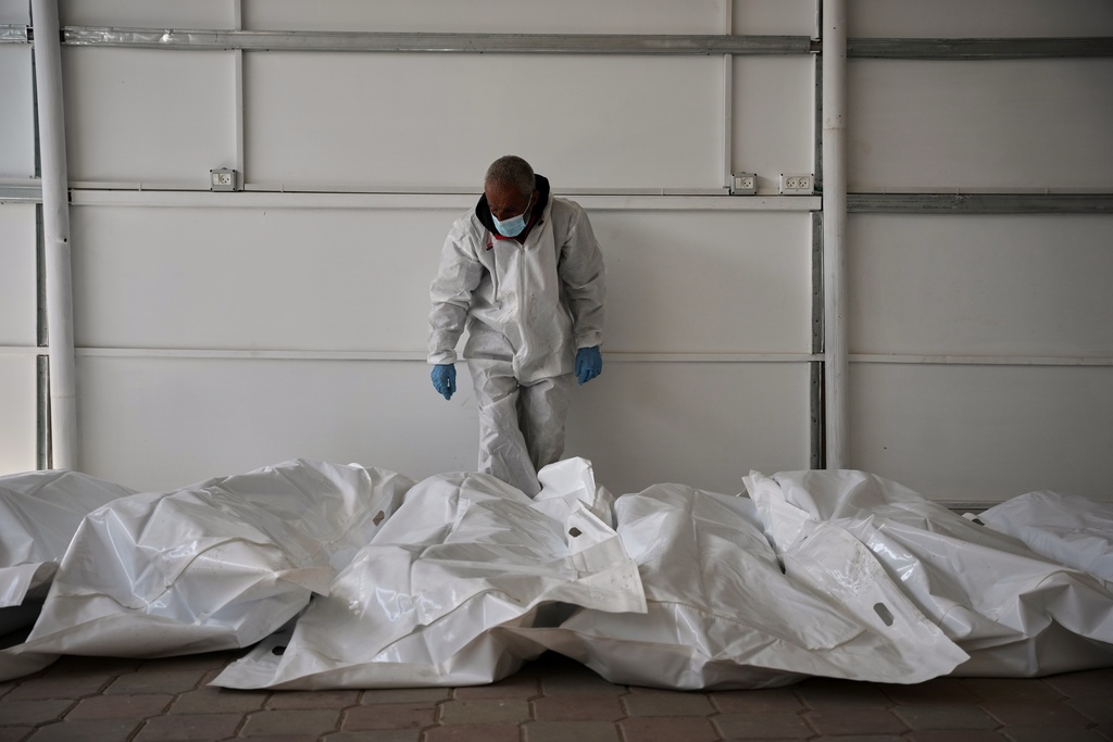 Bodies of unidentified Palestinians returned from Israel as part of the ceasefire deal are placed at a warehouse in Nasser Hospital in Khan Younis, Gaza Strip, Friday, Oct. 31, 2025. (AP Photo/Abdel Kareem Hana)