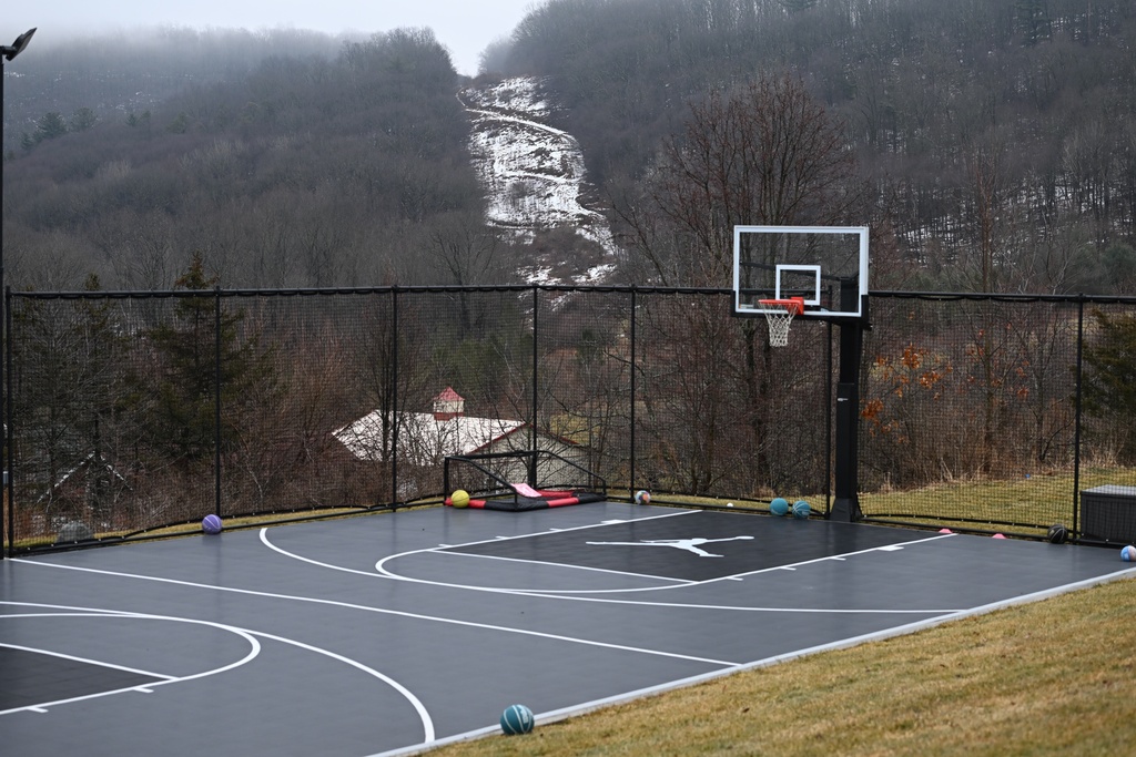 The snow-covered corridor once used for a since-removed residential power line is visible behind the basketball court and barn on John Zola's property where the local power utility wants to build a 500-kilovolt power line on towers as tall as 240 feet across his land, March 4, 2026, in Sugarloaf, Pa. (AP Photo/Marc Levy)