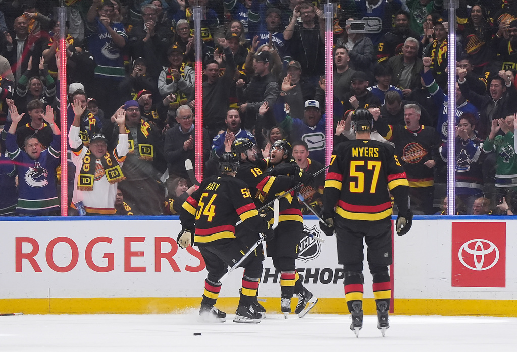 Vancouver Canucks' Kiefer Sherwood, back right, celebrates after his goal with Drew O'Connor (18) and Aatu Raty (54) as Tyler Myers (57) skates to join them during the first period of an NHL hockey game against the Calgary Flames in Vancouver, British Columbia, Thursday, Oct. 9, 2025. (Darryl Dyck/The Canadian Press via AP)