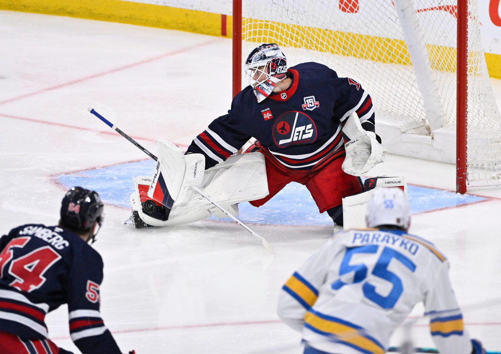 Winnipeg Jets goaltender Eric Comrie, top, makes a save against St. Louis Blues' Colton Parayko (55) during third-period NHL hockey game action in Winnipeg, Manitoba, Sunday March 15, 2026. (Fred Greenslade/The Canadian Press via AP) Press via AP)