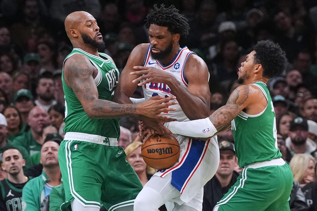 Philadelphia 76ers center Joel Embiid, center, loses control of the ball while trapped by Boston Celtics forward Xavier Tillman, left, guard Anfernee Simons, right, during the first half of an NBA basketball game, Wednesday, Oct. 22, 2025, in Boston. (AP Photo/Charles Krupa)