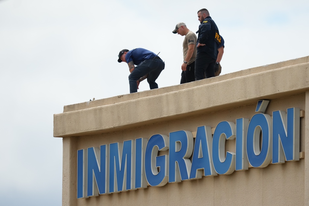 Law enforcement agents look around the roof of a building near the scene of a shooting at a U.S. Immigration and Customs Enforcement office in Dallas on Wednesday, Sept. 24, 2025. (AP Photo/Julio Cortez)
