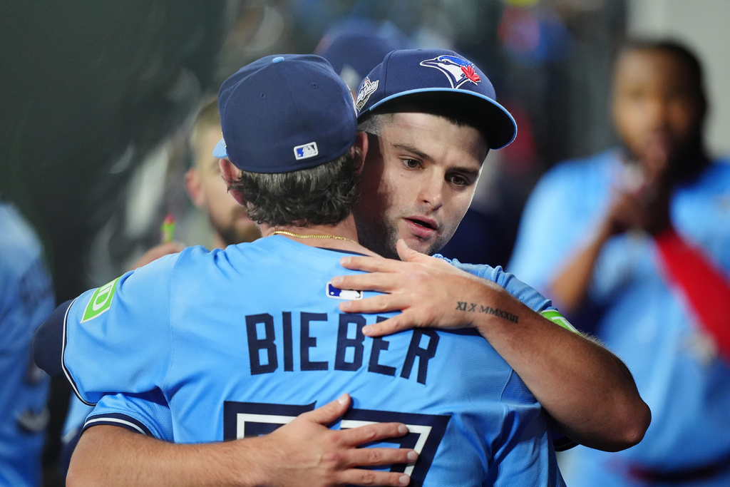 Toronto Blue Jays pitcher Shane Bieber (57) hugs teammate pitcher Mason Fluharty after Fluharty finished out the bottom of the sixth inning of Game 4 World Series playoff MLB baseball action against the Los Angeles Dodgers in Los Angeles on Tuesday, Oct. 28, 2025. (Frank Gunn/The Canadian Press via AP)