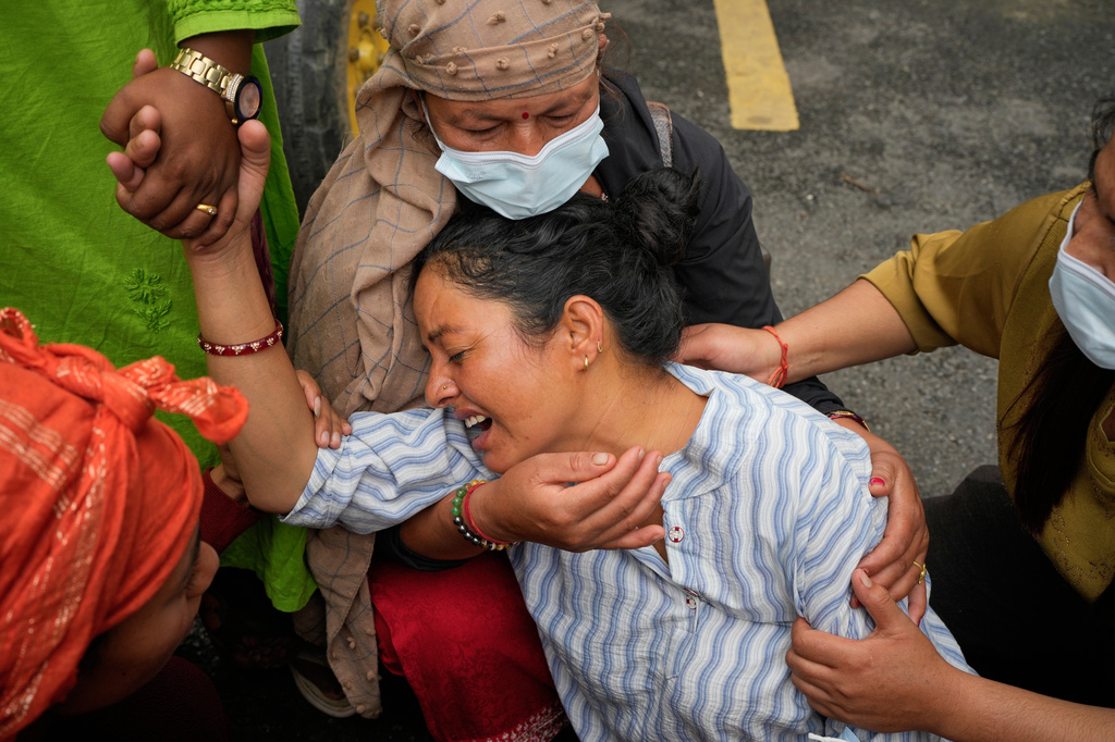 Relatives console Muna Khadka, center, who lost her son Aayush Khada, in flash floods, during mass burials in Chitwan, Nepal, Monday, Aug. 31, 2026. (AP Photo/Dar Yasin)