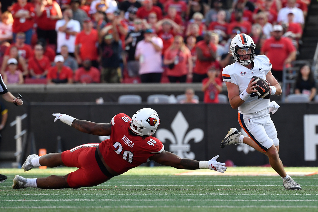 Virginia quarterback Chandler Morris (4) avoids the reach of Louisville Cardinals defensive lineman Rene Konga (90) during the second half of an NCAA college football game in Louisville, Ky., Saturday, Oct. 4, 2025. (AP Photo/Timothy D. Easley)