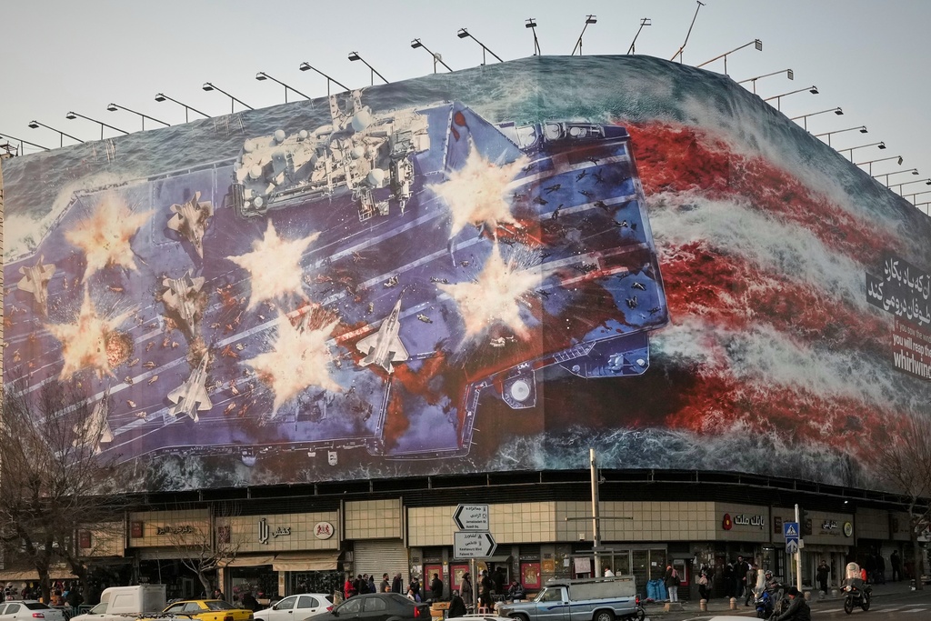 A billboard depicting a damaged U.S. aircraft carrier with disabled fighter jets on its deck and a sign reading in Farsi and English, "If you sow the wind, you'll reap the whirlwind," is seen at Enqelab-e-Eslami (Islamic Revolution) Square in Tehran, Iran, Sunday, Jan. 25, 2026. (AP Photo/Vahid Salemi)