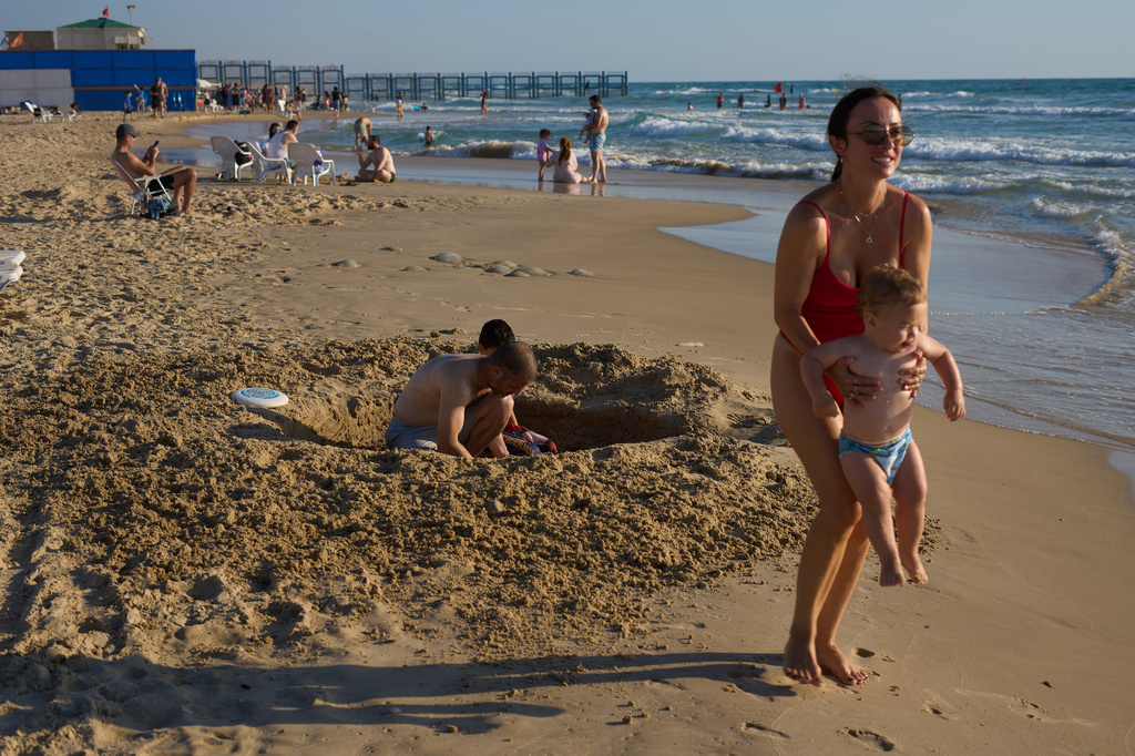 A family enjoys the Mediterranean Sea in Rishon LeZion, Tuesday, June 23, 2026. The beach is located near a military firing range that had been used for decades and is slated to be cleared and opened for public use. (AP Photo/Ariel Schalit)