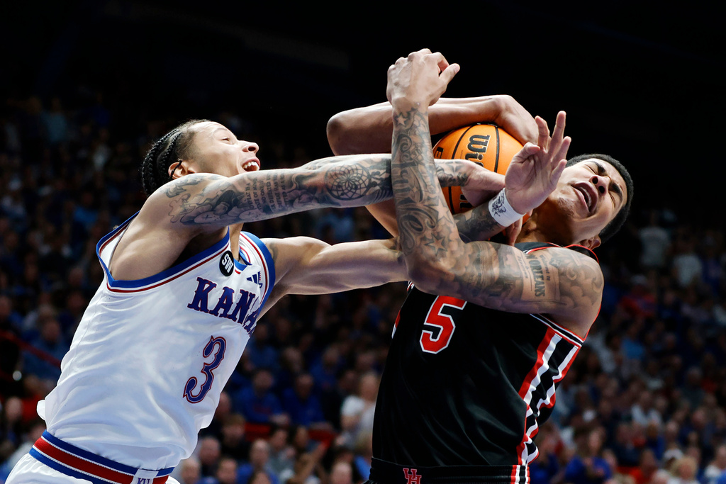 Kansas guard Tre White (3) and Houston center Chris Cenac Jr. (5) vie for a rebound during the first half of an NCAA college basketball game Monday, Feb. 23, 2026, in Lawrence, Kan. (AP Photo/Colin E. Braley)