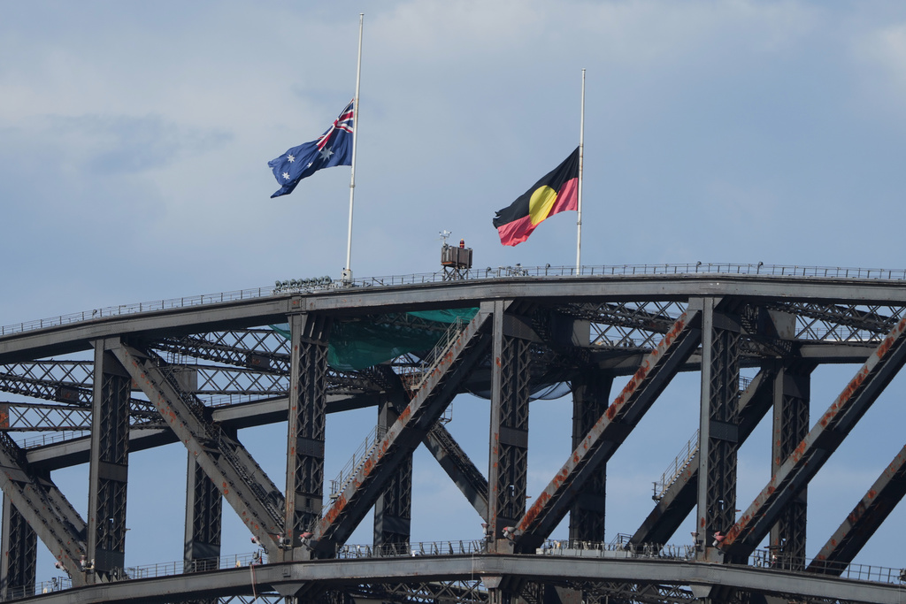 Australian and Aboriginal flags fly at half staff on the Sydney Harbour Bridge during a National Day of Reflection to honour the victims of the last Sunday's terrorist attack at Bondi Beach, Sunday, Dec. 21, 2025. (AP Photo/Mark Baker)