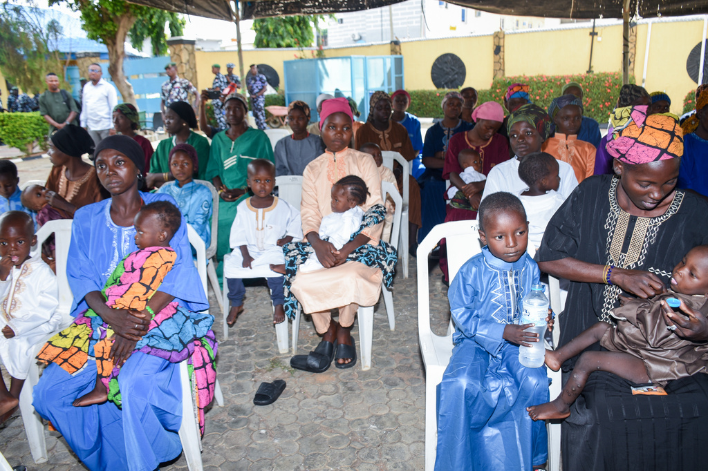 Women and children sit in the courtyard of a hotel where they are staying while waiting for the state governor to address them in Ilorin, Nigeria, Friday, Aug. 7, 2026, after being rescued from a forest where they were held following their abduction from the Woro community by gunmen in February. (AP Photo/Abubakar Khadijat)