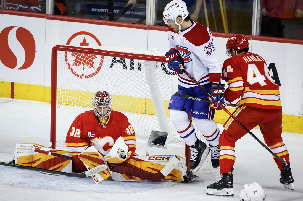 Montreal Canadiens' Juraj Slafkovsky (20) jumps out of the way as Calgary Flames goalie Dustin Wolf (32) grabs a shot during the first period of an NHL hockey game in Calgary, Alberta, Wednesday, Oct. 22, 2025. (Jeff McIntosh/The Canadian Press via AP)