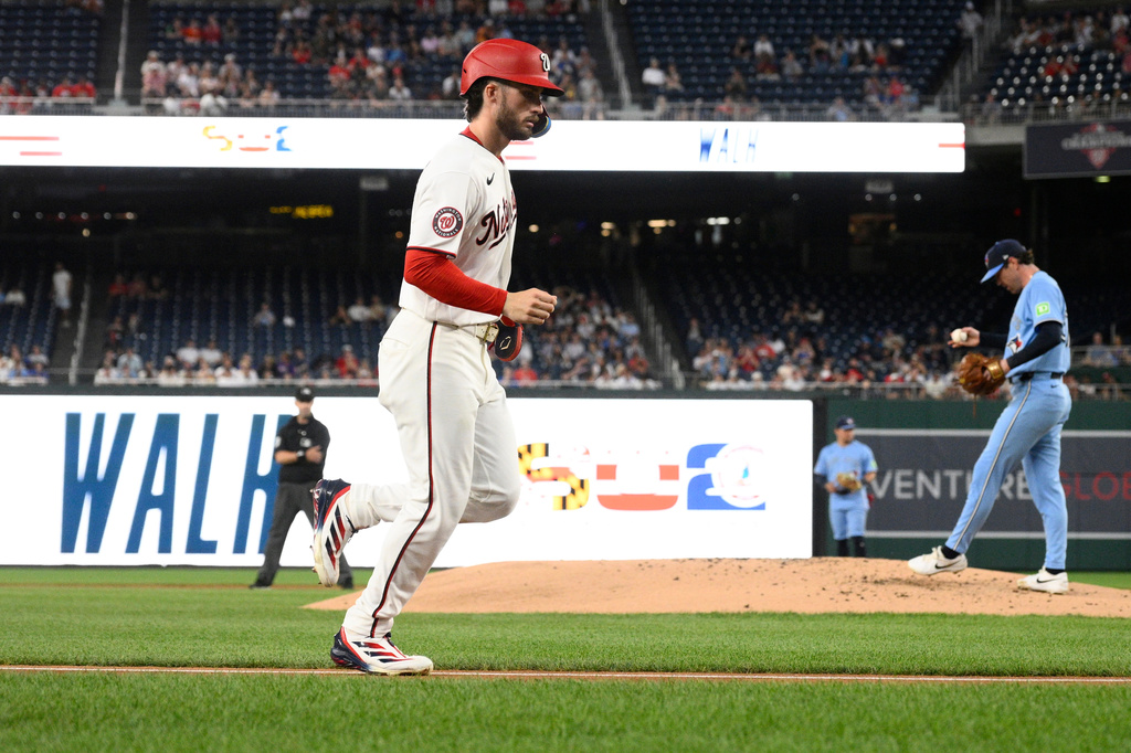 Washington Nationals' Dylan Crews, left, goes towards home to score on a bases loaded walk to Daylen Lile against Toronto Blue Jays pitcher Shane Bieber, right, during the first inning of a baseball game, Tuesday, July 28, 2026, in Washington. (AP Photo/Nick Wass)