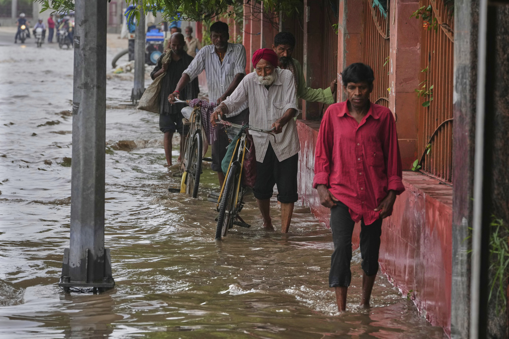 Commuters wade through the flooded water on a road after the river Yamuna, swollen by incessant rain in the higher regions, overran its banks, in New Delhi, India, Friday, Sept. 5, 2025. (AP Photo/Manish Swarup)