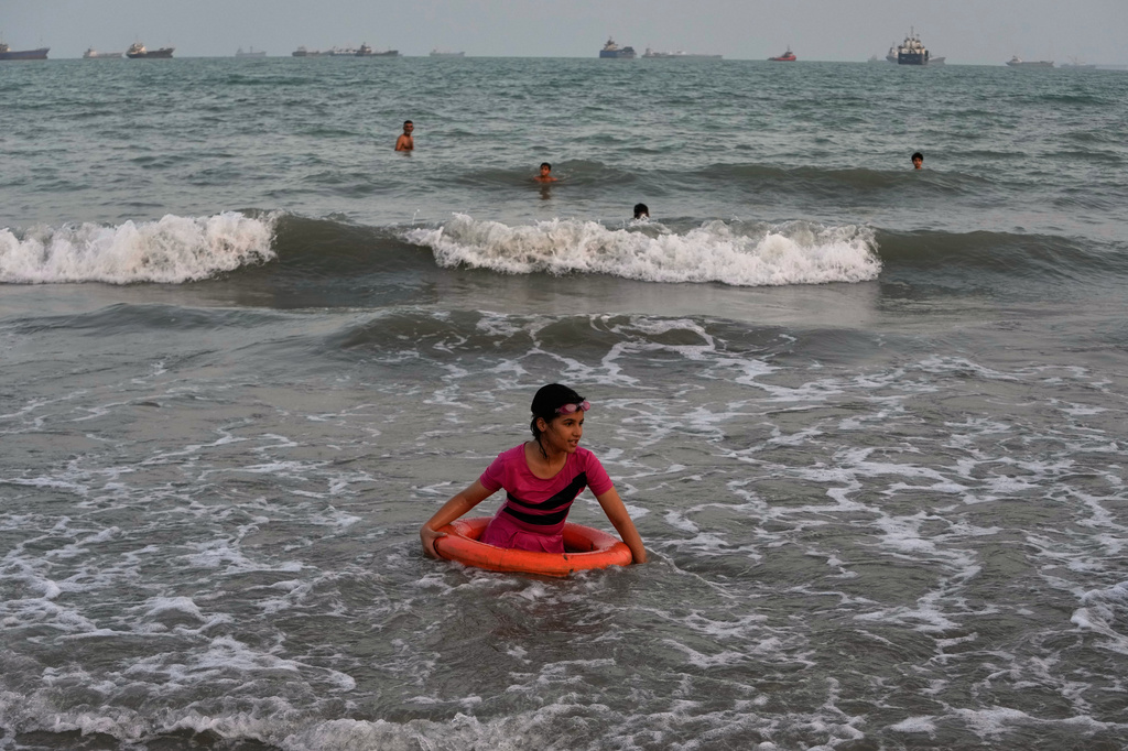 A girl plays in the water with a swim ring as commercial vessels lie anchored in the Strait of Hormuz off Bandar Abbas, Iran, Friday, Sept. 4, 2026. (AP Photo/Vahid Salemi)