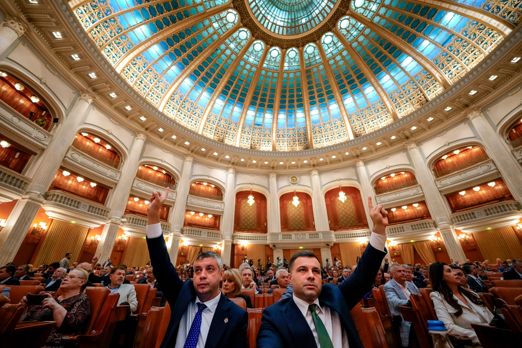 Romanian lawmakers raise their hands at the start of a joint parliament session ahead of a vote of confidence for the new government team led by Romanian Prime Minister designate Adrian Vestea, in Bucharest, Romania, Monday, June 22, 2026. (AP Photo/Vadim Ghirda)