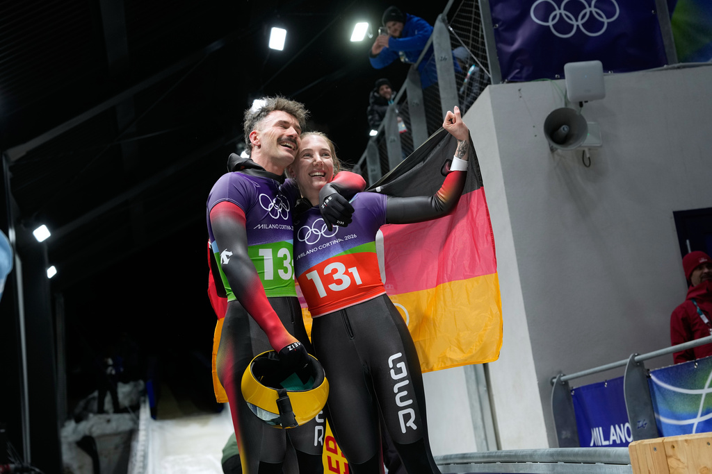 Germany's Axel Jungk, left, and Germany's Susanne Kreher, right, celebrate at the finish during the skeleton mixed team competition at the 2026 Winter Olympics, in Cortina d'Ampezzo, Italy, Sunday, Feb. 15, 2026. (AP Photo/Alessandra Tarantino)