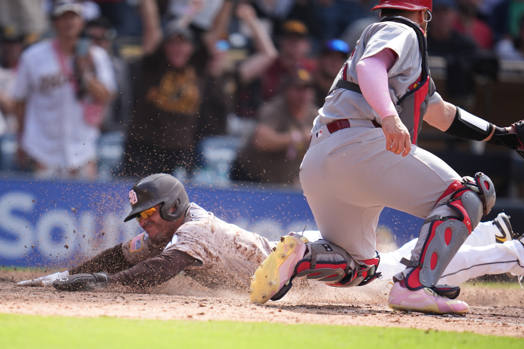 San Diego Padres' Nick Castellanos, left, slides in to score from third base off a walk off sacrifice fly by Manny Machado as St. Louis Cardinals catcher Pedro Pagés waits for the throw during the tenth inning of a baseball game Sunday, May 10, 2026, in San Diego. (AP Photo/Gregory Bull)