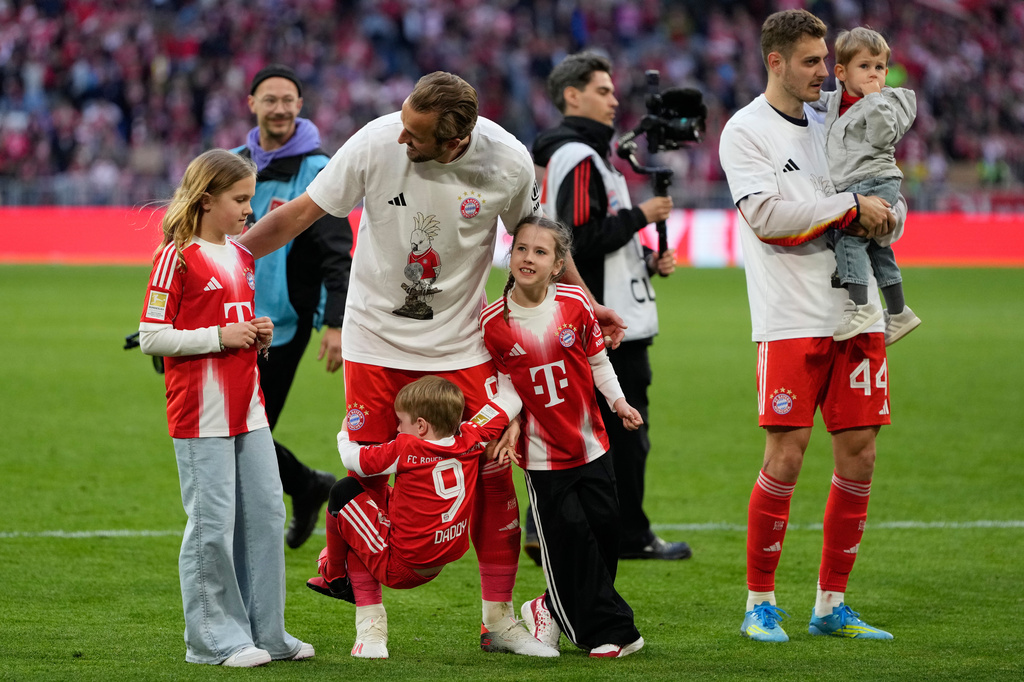 Bayern's Harry Kane hugs his kids after his team clinched the German league title after a Bundesliga soccer match between Bayern and Stuttgart in Munich, Germany, Sunday, April 19, 2026. (AP Photo/Matthias Schrader)