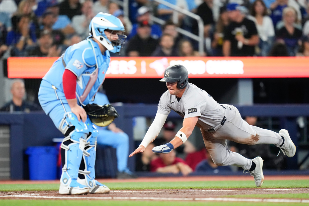 New York Yankees' Max Schuemann reaches home to score in front of Toronto Blue Jays catcher Alejandro Kirk after an RBI single from Anthony Volpe during the second inning of a baseball game in Toronto on Sunday June 14, 2026. (Chris Young/The Canadian Press via AP)