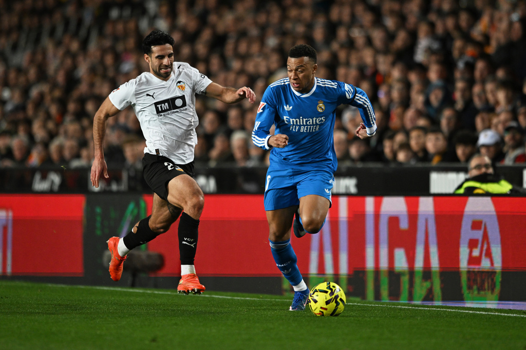 Real Madrid's Kylian Mbappe, right, and Valencia's Eray Comert challenge for the ball during the Spanish La Liga soccer match between Valencia and Real Madrid in Valencia, Spain, Sunday, Feb. 8, 2026. (AP Photo/Francisco Macia)