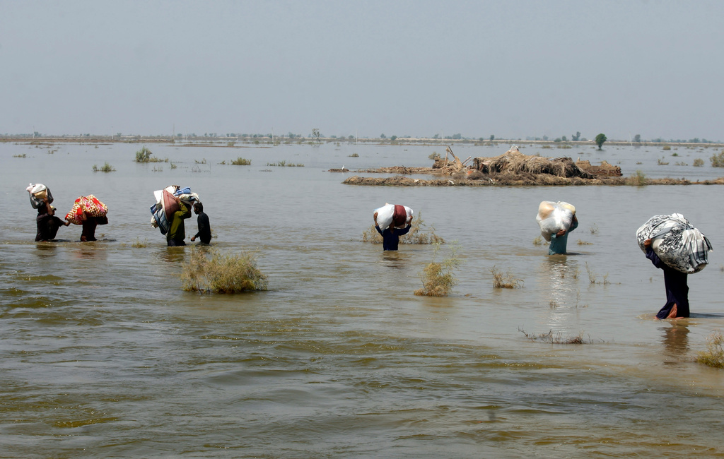 FILE - Victims of heavy flooding from monsoon rains carry relief aid through floodwaters in the Qambar Shahdadkot district of Sindh Province, Pakistan, Sept. 9, 2022. (AP Photo/Fareed Khan, File)