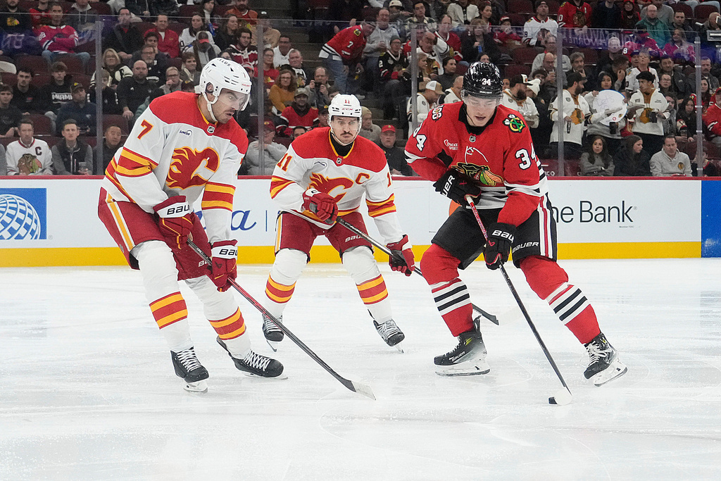 Calgary Flames defenseman Kevin Bahl (7), left, defends Chicago Blackhawks center Colton Dach (34) during the second period of an NHL hockey game Tuesday, Nov. 18, 2025, in Chicago. (AP Photo/David Banks)
