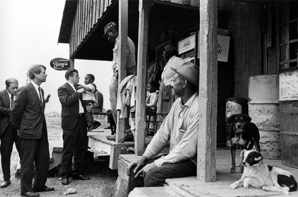 FILE - Sen. Robert F. Kennedy, D-N.Y., left, talks with a group of people in front of a country store during his tour of the Mississippi Delta, while investigating the federal antipoverty program, near Greenville, Miss., April 11, 1967. Next to Kennedy is Kenneth Dean of the Mississippi Council on Human Relations, who is holding a child suffering from a diet deficiency. (AP Photo/Jack Thornell, File)