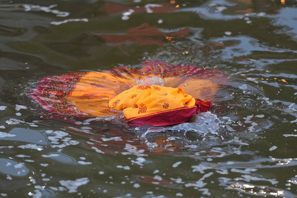 A woman devotee takes a dip after praying to the sun in the river Yamuna during the Chhath festival, which is celebrated for the well-being and prosperity of one's family, in New Delhi, India, Monday, Oct. 27, 2025. (AP Photo/Manish Swarup)