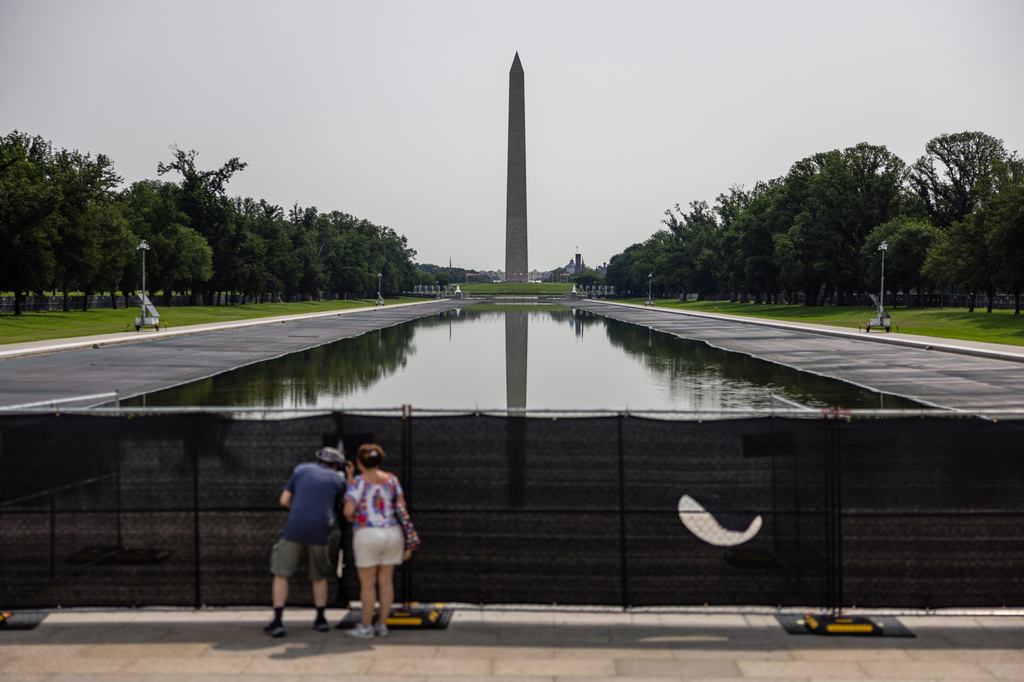 Visitors look at the drained Lincoln Memorial Reflecting Pool, Wednesday, Aug. 12, 2026, in Washington. The Washington Monument is rear. (AP Photo/Tierney L. Cross)