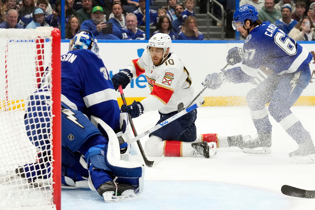 Florida Panthers left wing A.J. Greer (10) shoots on Tampa Bay Lightning goaltender Jonas Johansson (31) from his knees as Tampa Bay Lightning's Declan Carlile (67) defends during the first period of an NHL hockey game Monday, Dec. 15, 2025, in Tampa, Fla. (AP Photo/Chris O'Meara)