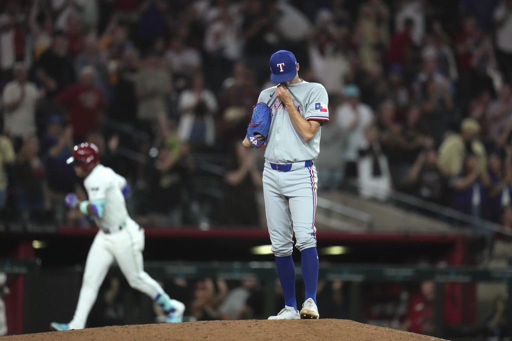 Texas Rangers pitcher Hoby Milner, right, pauses on the pitcher's mound after giving up a three-run home run to Arizona Diamondbacks' Ketel Marte, left, during the seventh inning of a baseball game Tuesday, Sept. 2, 2025, in Phoenix. (AP Photo/Ross D. Franklin)