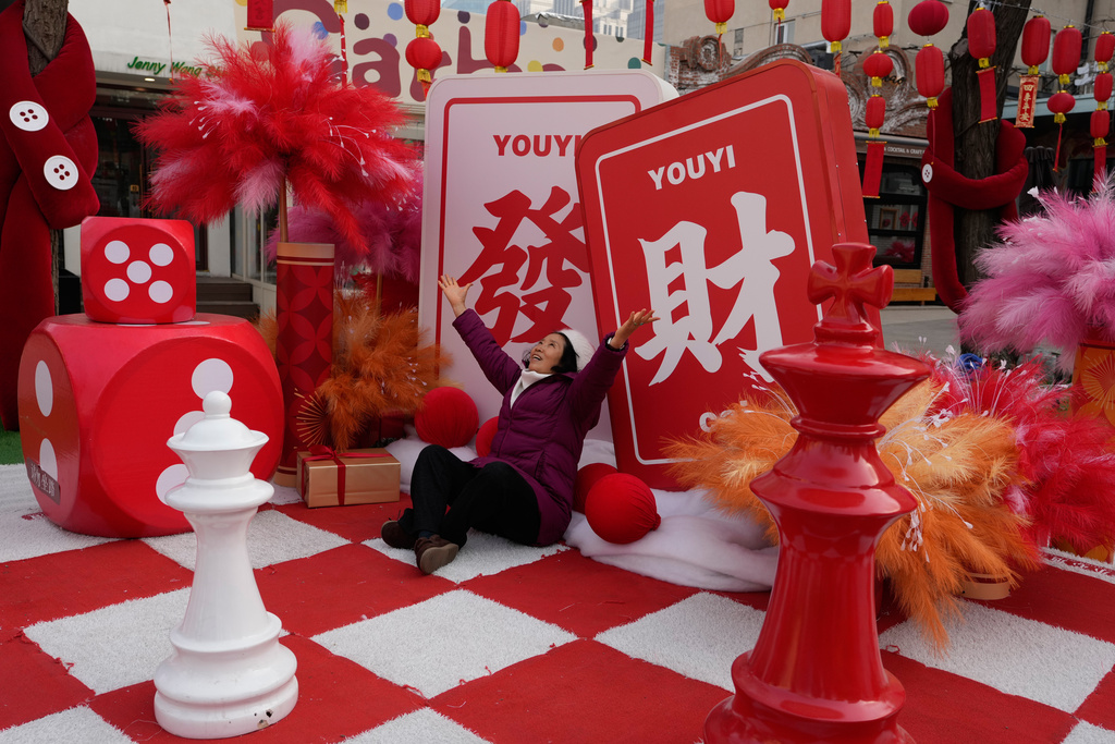 A woman reacts for a photo near the words "Get Rich" in Beijing, China, Thursday, Jan. 15, 2026. (AP Photo/Ng Han Guan)