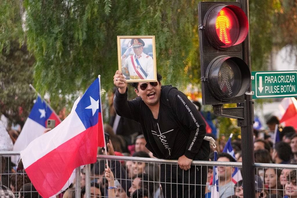 A supporter of Jose Antonio Kast, presidential candidate of the opposition Republican Party, holds a portrait of former military dictator Gen. Augusto Pinochet during his celebration rally after the presidential runoff election in Santiago, Chile, Sunday, Dec. 14, 2025. (AP Photo/Matias Delacroix)