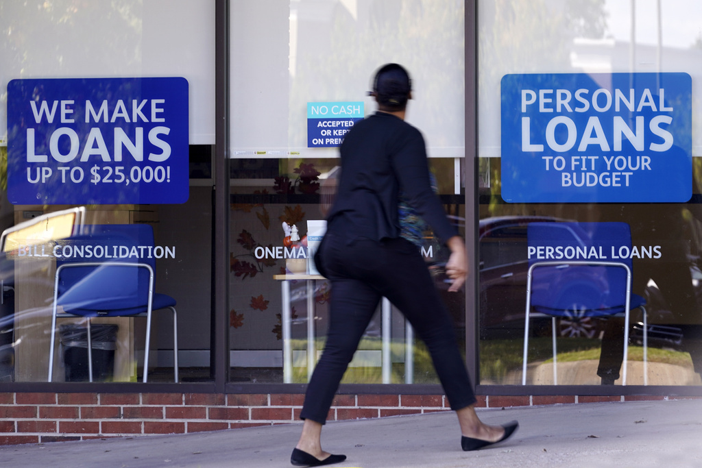 FILE - A woman walks past a personal finance loan office Thursday, Oct. 1, 2020, in Franklin, Tenn. (AP Photo/Mark Humphrey, File)