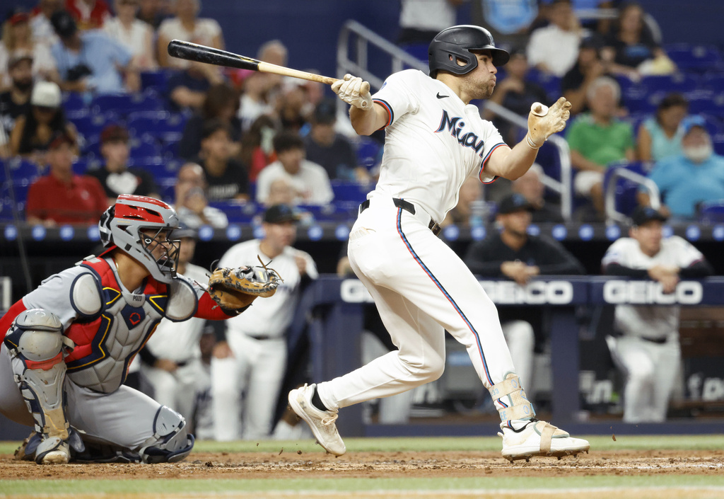 Miami Marlins' Jakob Marsee, right, singles in front of St. Louis Cardinals catcher Yohel Pozo during the third inning of a baseball game Wednesday, Aug. 20, 2025, in Miami. (AP Photo/Rhona Wise)