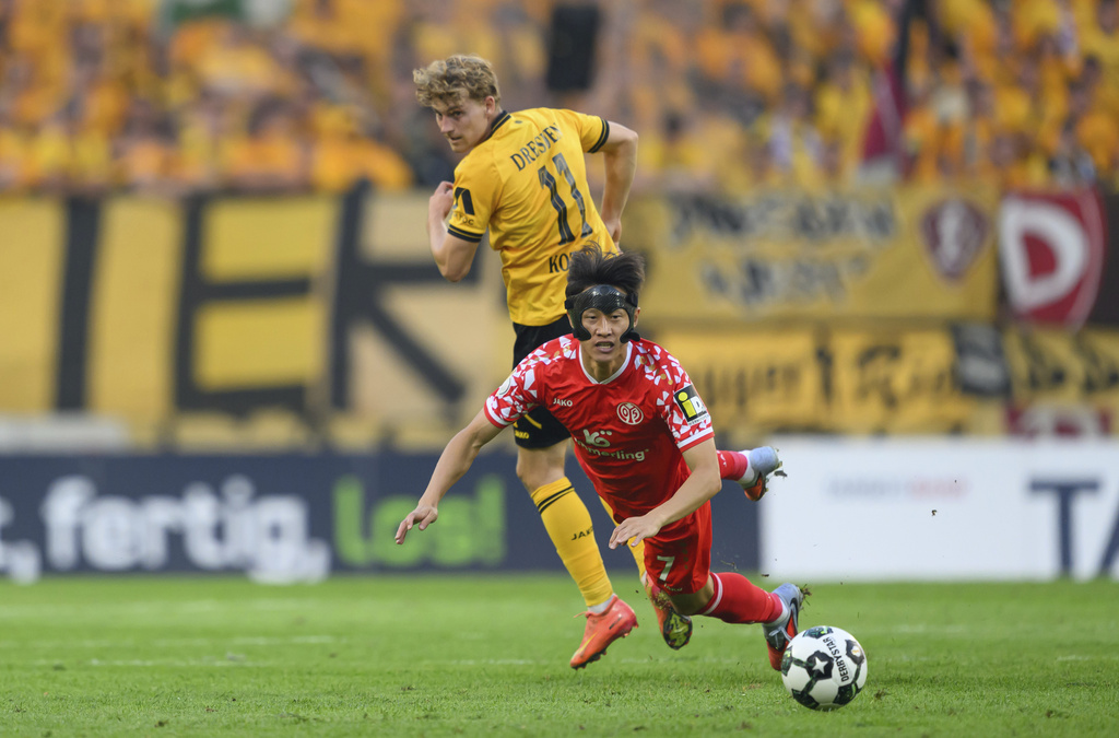 Dresden's Dominik Kother, rear, and Mainz' Jae-sung Lee, front, challenge for the ball during the German soccer cup first round match between Dynamo Dresden and FSV Mainz 05 in Dresden, Germany, Monday, Aug. 18, 2025. (Robert Michael/dpa via AP)