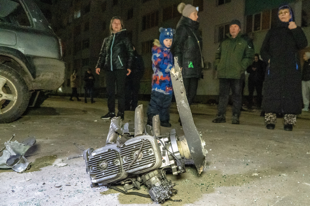 People look at fragments of a Russian drone that hit residential neighbourhood during air attack in Kharkiv, Ukraine, late Monday, March 9, 2026. (AP Photo/Andrii Marienko)