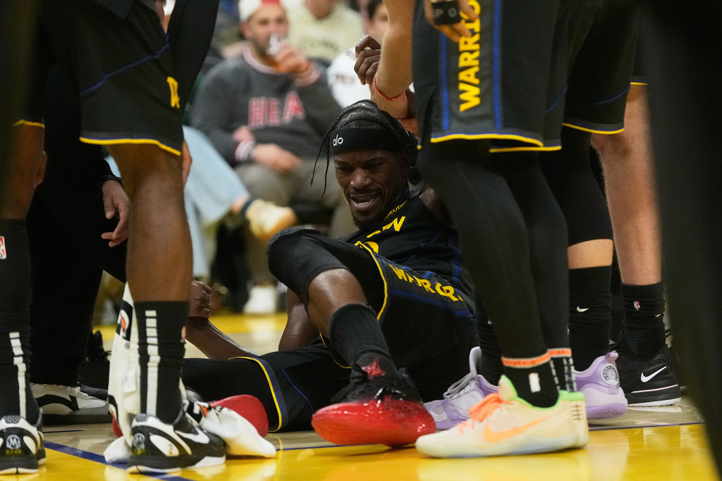 Golden State Warriors forward Jimmy Butler III, middle, is helped up by teammates during the second half of an NBA basketball game against the Miami Heat in San Francisco, Monday, Jan. 19, 2026. (AP Photo/Jeff Chiu)