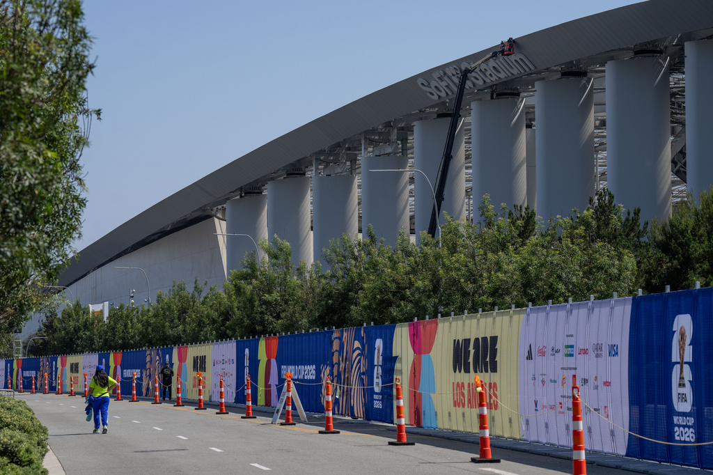 A person walks past temporary fencing with FIFA World Cup 2026 signage outside SoFi Stadium, Friday, June 5, 2026, in Inglewood, Calif. (AP Photo/Jae C. Hong)