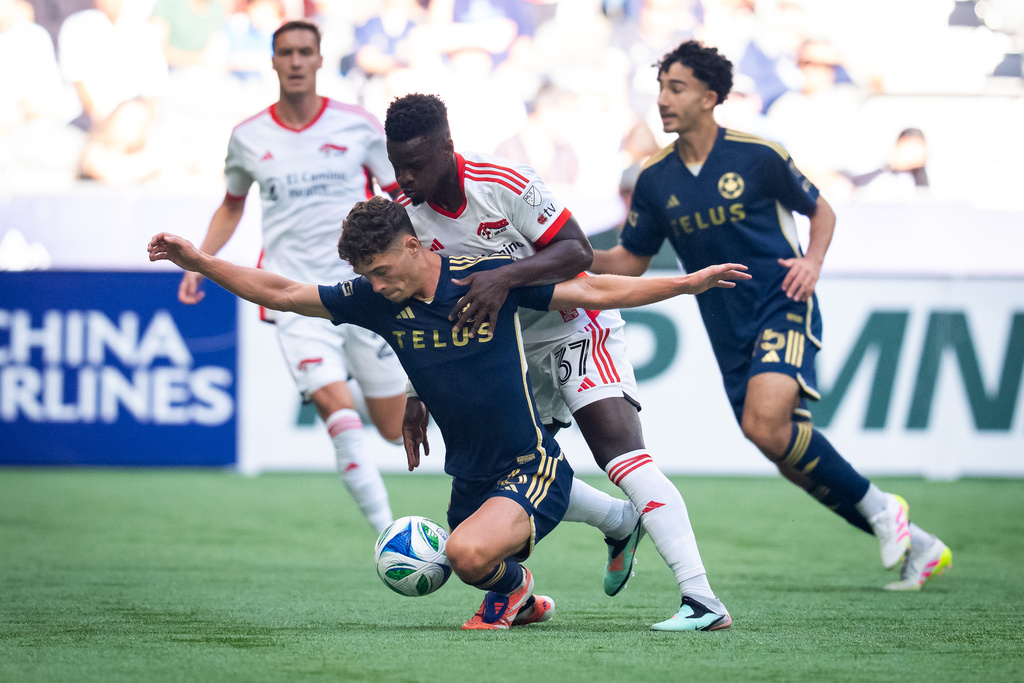 Vancouver Whitecaps' Sebastian Berhalter, front, falls while battling San Jose Earthquakes' Ronaldo Vieira (37) for the ball during the first half of an MLS soccer match in Vancouver, British Columbia, Sunday, Oct. 5, 2025. (Ethan Cairns/The Canadian Press via AP)