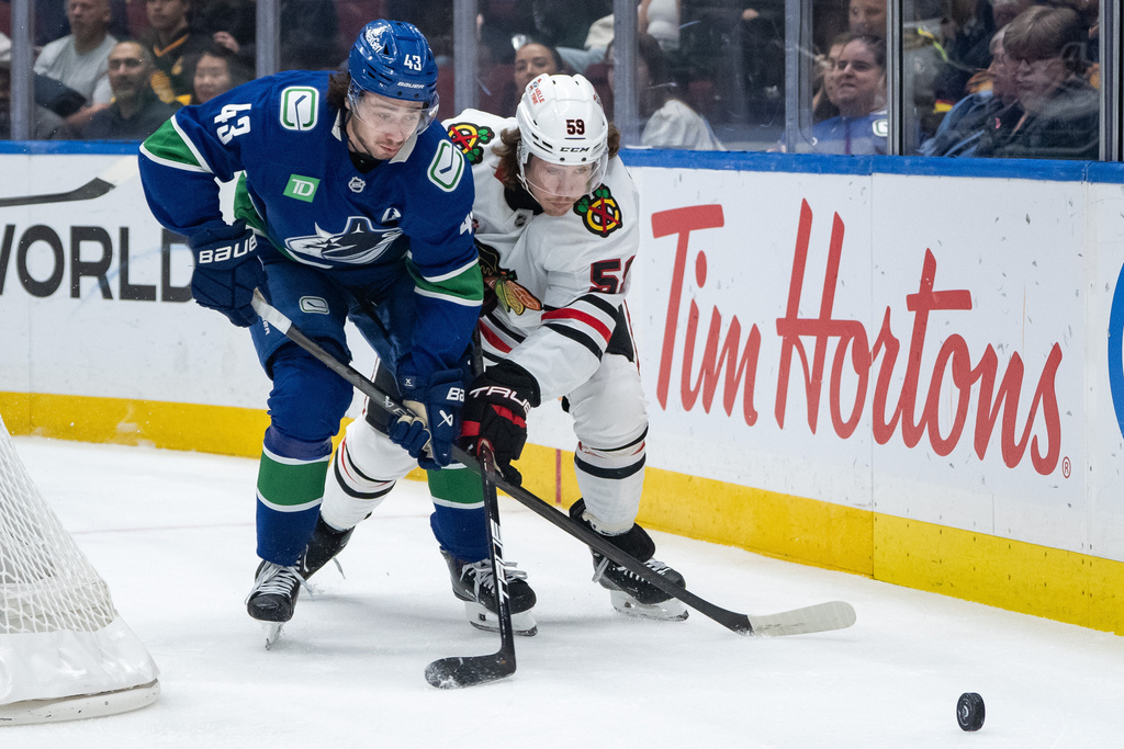 Vancouver Canucks' Quinn Hughes (43) and Chicago Blackhawks' Tyler Bertuzzi (59) vie for the puck during the first period of an NHL hockey game in Vancouver, on Wednesday, Nov. 5, 2025. (Ethan Cairns/The Canadian Press via AP)