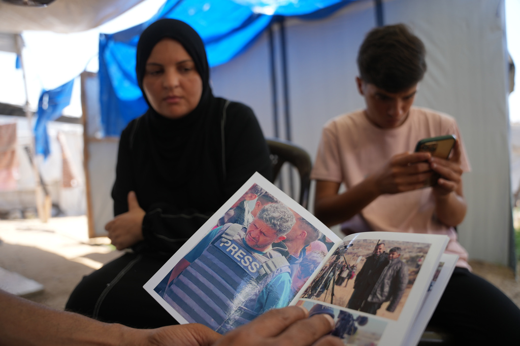 Family members of Palestinian journalist Hussam al-Masri, who worked as a freelance journalist for Reuters and was killed in an Israeli airstrike targeting the Nasser Hospital building in Khan Younis on Aug. 25, 2025, look at his photos in Khan Younis, southern Gaza Strip, Aug. 16, 2026. (AP Photo/Abdel Kareem Hana)