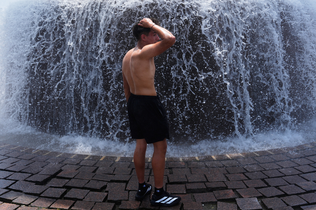 Emmanuel Lopez tries to cool off during a run from hot weather at Dodge Fountain at Hart Plaza in Detroit, Tuesday, June 30, 2026. (AP Photo/Paul Sancya)