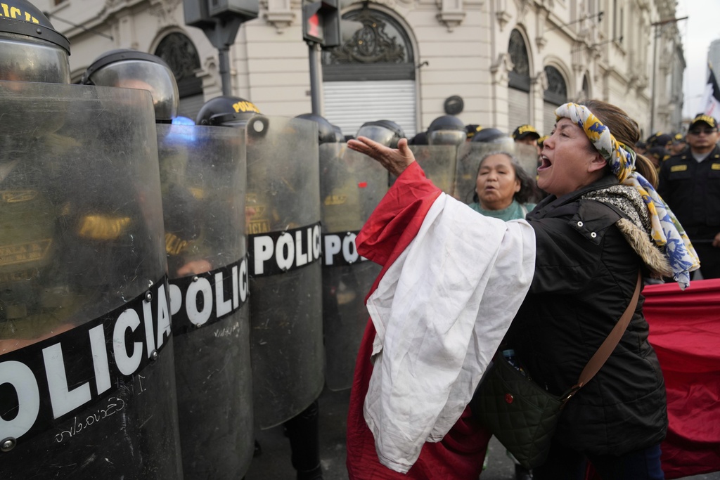 An anti-government protester pleads with riot police blocking the path at San Martin plaza during a rally against President Dina Boluarte's economic and social policies in Lima, Peru, Saturday, Sept. 20, 2025. (AP Photo/Martin Mejia)