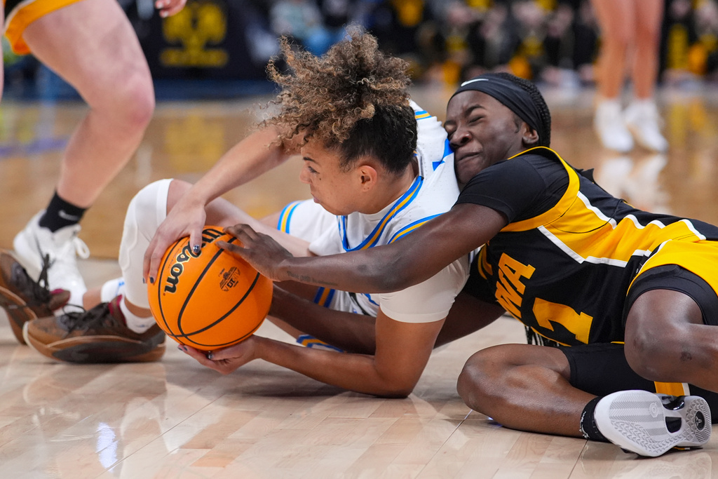 Iowa guard Taylor Stremlow (1) and UCLA guard Kiki Rice (1) go for a loose ball in the first half of an NCAA college basketball game in the finals of the Big Ten Conference tournament, Sunday, March 8, 2026 in Indianapolis. (AP Photo/Michael Conroy)