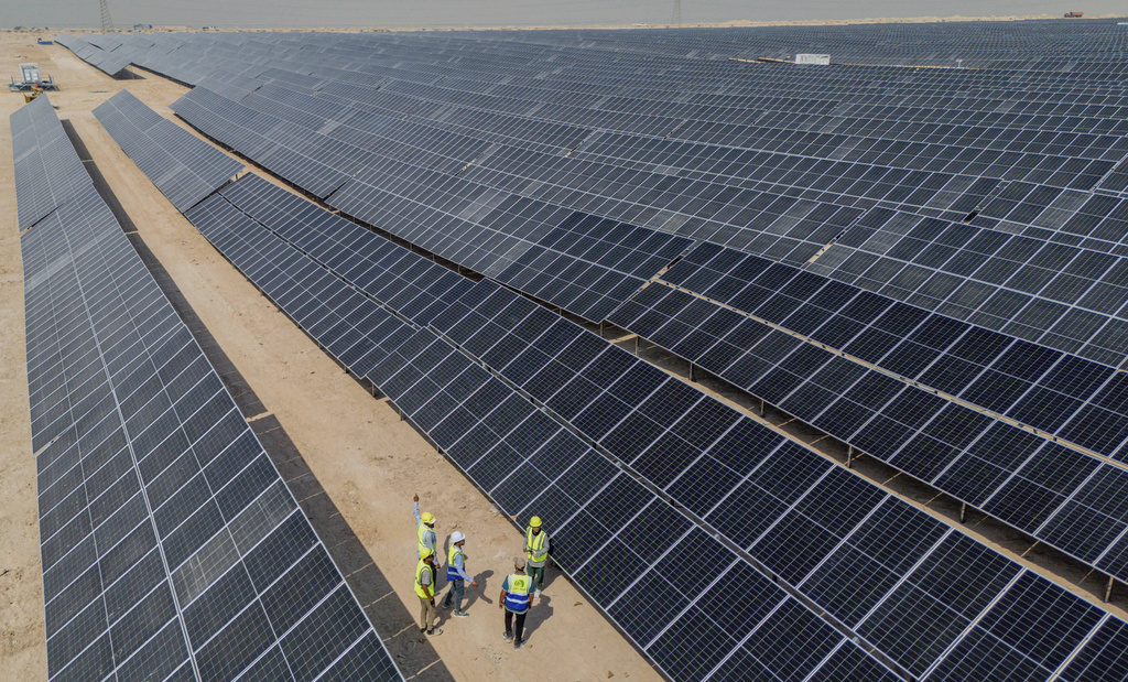 Workers walk between solar panels at a newly opened industrial-scale solar power plant in Karbala, Iraq, Wednesday, Sept. 17, 2025. (AP Photo/Anmar Khalil)