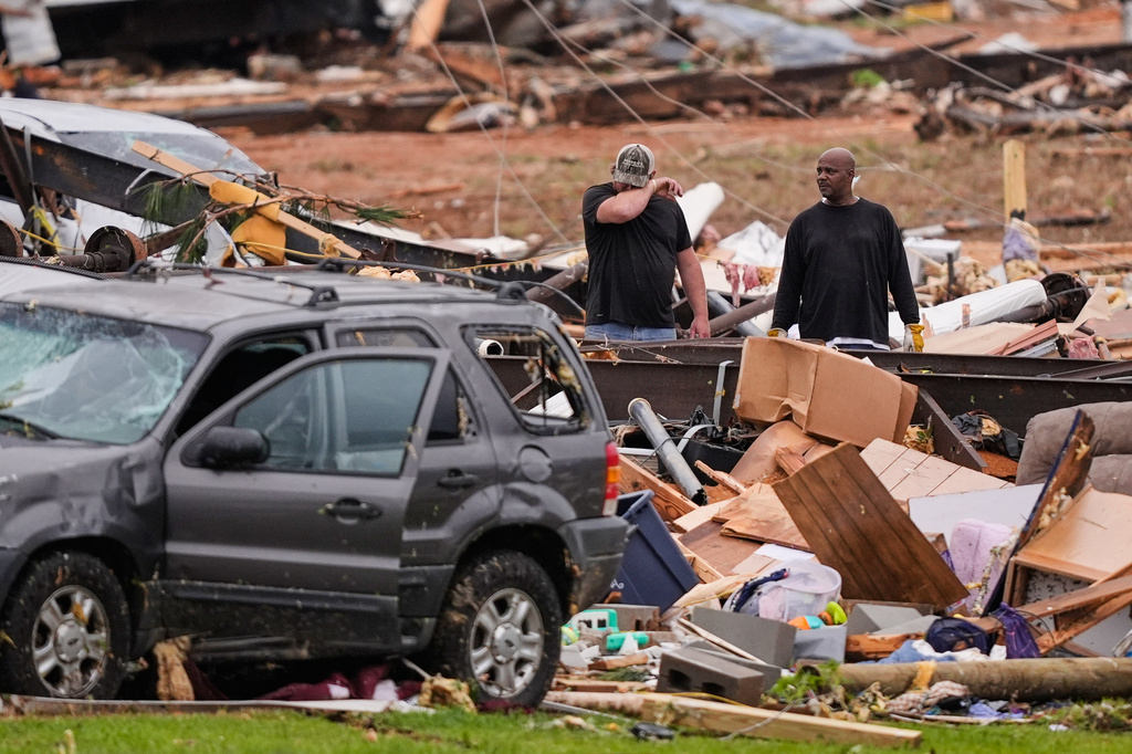 People stand among debris at Gene's Mobile Home Supply, a trailer park in Bogue Chitto, Miss., Thursday, May, 7, 2026, after a tornado cut across the state. (AP Photo/Gerald Herbert)